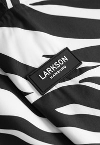 Černobílá látka s zebrovým vzorem a našívkou ve tvaru černého obdélníku s nápisem "LARKSON HAMBURG".