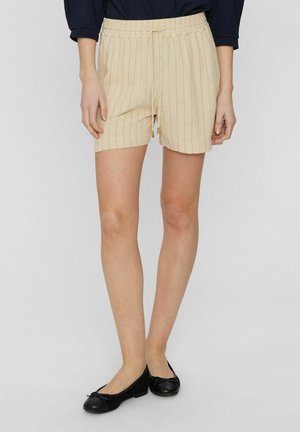 Helle beige Shorts mit vertikalen Streifen, elastischem Bund mit Kordelzug und Seitentaschen, kombiniert mit schwarzen flachen Schuhen.