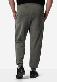 Grijze joggers met een ontspannen pasvorm, voorzien van een elastische tailleband en een achterzak. Materiaal lijkt zacht met een gladde textuur.