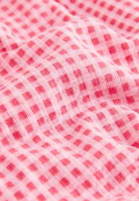 Tissu rose avec un motif gaufré en nid d'abeille texturé présentant des grilles carrées en relief dans des nuances alternées de rose.