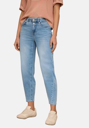 Vaqueros azul claro de talle alto con cierre de doble botón, usados con zapatillas beige y una camiseta de manga corta a rayas rojas y blancas.