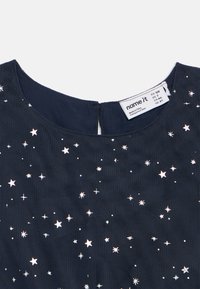 Mørkeblå stoff med hvite stjerne mønstre og en "namnet" kleslabel som viser størrelse og opprinnelsesdetaljer.