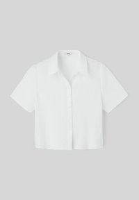 Chemise blanche à manches courtes en tissu texturé, avec un col et six boutons sur le devant.