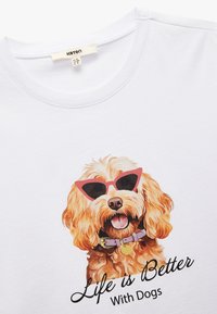 Witte katoenen t-shirt met een afbeelding van een hond in roze zonnebrillen, met de tekst "Het leven is beter met honden" in vetgedrukte zwarte letters.