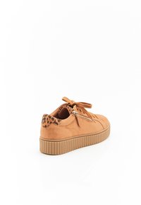 Baskets en daim beige avec une semelle en caoutchouc texturée et striée, un système de laçage à l'avant et des accents en imprimé léopard sur le talon, présentant un détail de fermeture éclair.