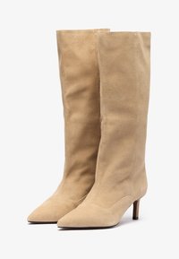 Beige suede knee-high boots with a pointed toe and a slim heel. Smooth texture, minimal design, and no visible hardware or accents.