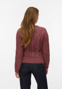 Fuzzy, cable-knit sweater in mauve, featuring ribbed sleeves and hem, worn with dark denim jeans, viewed from the back.