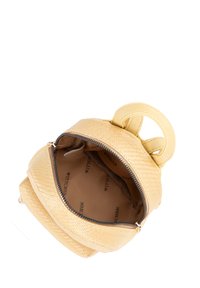 Zaino giallo in pelle sintetica con superficie testurizzata, manico superiore e chiusura con zip. Interno foderato con tessuto marchiato, che mostra lo spazio di stoccaggio.