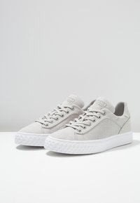 Trampki na płótnie, w jasnoszarym kolorze, o zaokrąglonym czubku, z fakturowaną białą gumową podeszwą, sześcioma otworami na sznurówki, logo na języku, subtelne detale w przeszyciach.