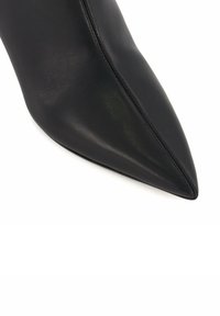 Black leather pointed-toe shoe with a smooth texture and a stitched seam along the side, showcasing a sleek, modern design.