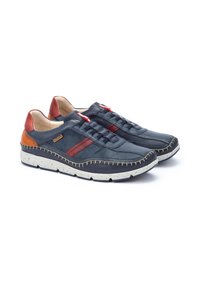 Sneakers in pelle blu con accenti rossi e marroni, design perforato, suola bianca con macchie e dettagli di cucitura a contrasto sui lati.