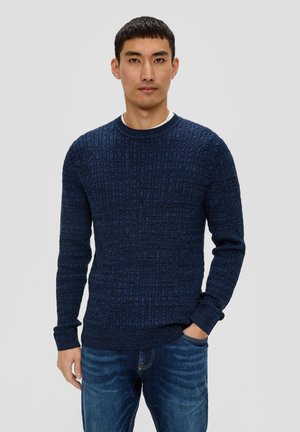 Navy knitted sweater with a textured pattern, crew neckline, and ribbed cuffs, paired with blue denim jeans.