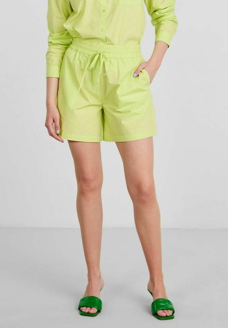 Light green shorts with an elastic waistband and drawstring; side pockets visible. Paired with green slide sandals. Smooth texture.