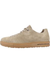 Beige suedey sneaker med rund tå, lyse snørebånd og en tan gummisåle. Har et teksturert sidedetail nær sålen.