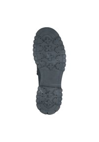 Suola di scarpa nera in gomma con scanalature profonde e motivi che presentano frecce e croci, progettata per garantire aderenza su diverse superfici.
