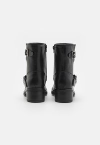 Czarne skórzane botki za kostkę o gładkiej teksturze, zaokrąglonym nosku, bocznymi zamkami błyskawicznymi oraz srebrnymi klamrami po zewnętrznej stronie. Słupkowy obcas.