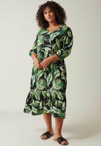 Losse midi-jurk van zwart materiaal met een levendig groen tropisch bladerenpatroon, driekwartmouwen en een gelaagde onderrand.
