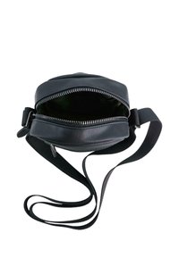 Runde schwarze Lederhandtasche mit Reißverschluss, ausgestattet mit einem langen verstellbaren Tragegurt und einer glatten Textur. Das Innere ist grün.