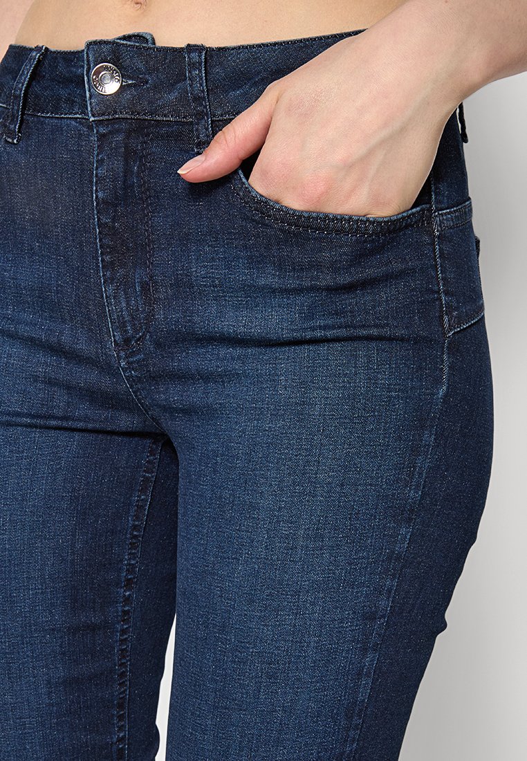 Jeans in denim blu scuro, con una vestibilità aderente. Comprendono una tasca anteriore e cuciture a contrasto vicino alla vita e ai bordi delle tasche.