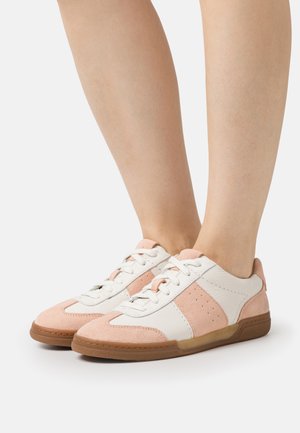 Des baskets présentant une combinaison de cuir blanc et de suède rose, avec un design bas, une semelle en caoutchouc et un système de laçage.