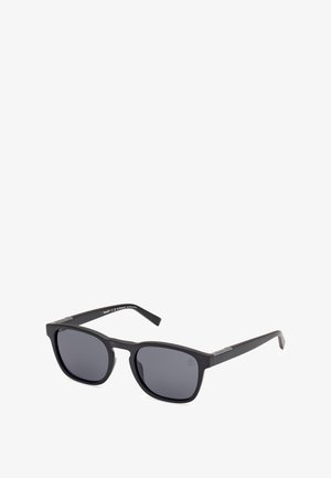 Occhiali da sole rettangolari neri con lenti scure, finitura opaca e un logo discreto sulla stecca. Il design sleek e minimalista ne esalta la versatilità.