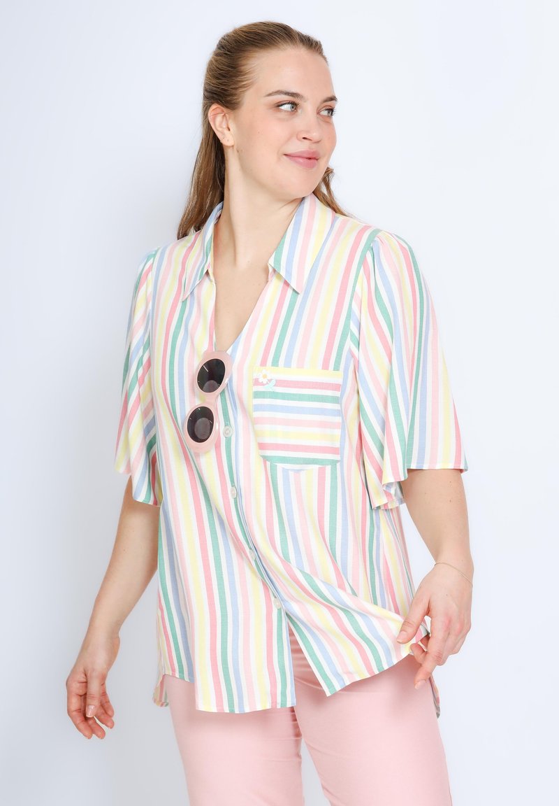 Chemise à manches courtes rayée dans des couleurs pastel avec une poche, ornée de boutons et d'un petit motif floral. Accentuée par des lunettes de soleil rondes.
