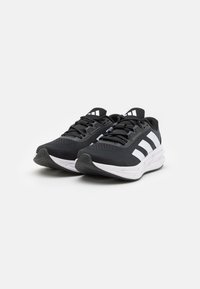 Black athletic shoes with a breathable mesh upper, white three-stripe design, cushioned sole, and textured rubber outsole for traction.