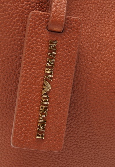 Brunet teksturert skinnveske med en gullfarget "Emporio Armani" logo-tag. Har et glatt håndtak og en rektangulær form.