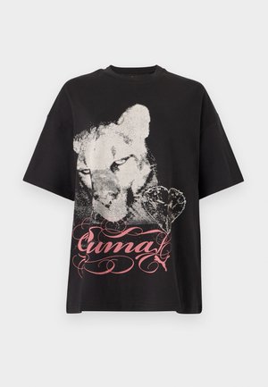 Μαύρο κοντομάνικο μπλουζάκι με μεγάλο φθαρμένο λευκό σχέδιο προσώπου λιονταριού, σχήμα καρδιάς και ροζ διακοσμητικό κείμενο "Puma" σε καλλιγραφικό στυλ μπροστά.