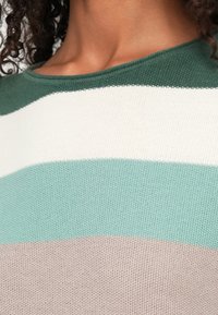 Pull en tricot avec un col rond, présentant des rayures horizontales en vert, blanc, bleu canard et beige. Tissu texturé au toucher doux.