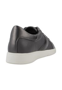 Zapatilla de cuero gris con un acabado suave, suela de goma blanca y detalle de franjas en los laterales. Cuello y talón suaves para mayor comodidad.