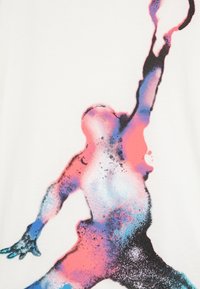 White t-shirt featuring a colorful silhouette print of a person raising one arm. The design uses blue, pink, and black spray paint effects.