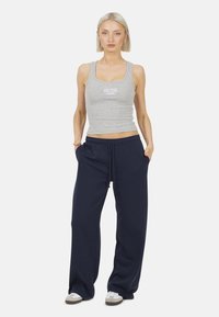 Canottiera grigia in cotone con la scritta "NEW YORK", abbinata a pantaloni tuta blu navy dal taglio ampio. I pantaloni presentano una vita elasticizzata e tasche laterali.