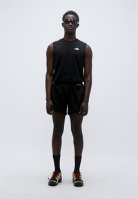 Μαύρο αθλητικό τοπ και σορτς, κατασκευασμένα από αναπνεύσιμο υλικό. Μαύρες κάλτσες και πολύχρωμα αθλητικά παπούτσια με υφασμένα πέλματα.