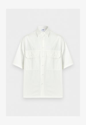 Chemise blanche à manches courtes avec col et deux poches à rabat sur le devant, présentée sur un fond clair uni.