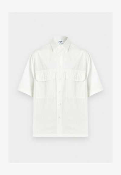 Λευκό κοντομάνικο πουκάμισο με κουμπιά, γιακά και δύο μπροστινές τσέπες με καπάκια, εμφανιζόμενο σε απλό φωτεινό φόντο.