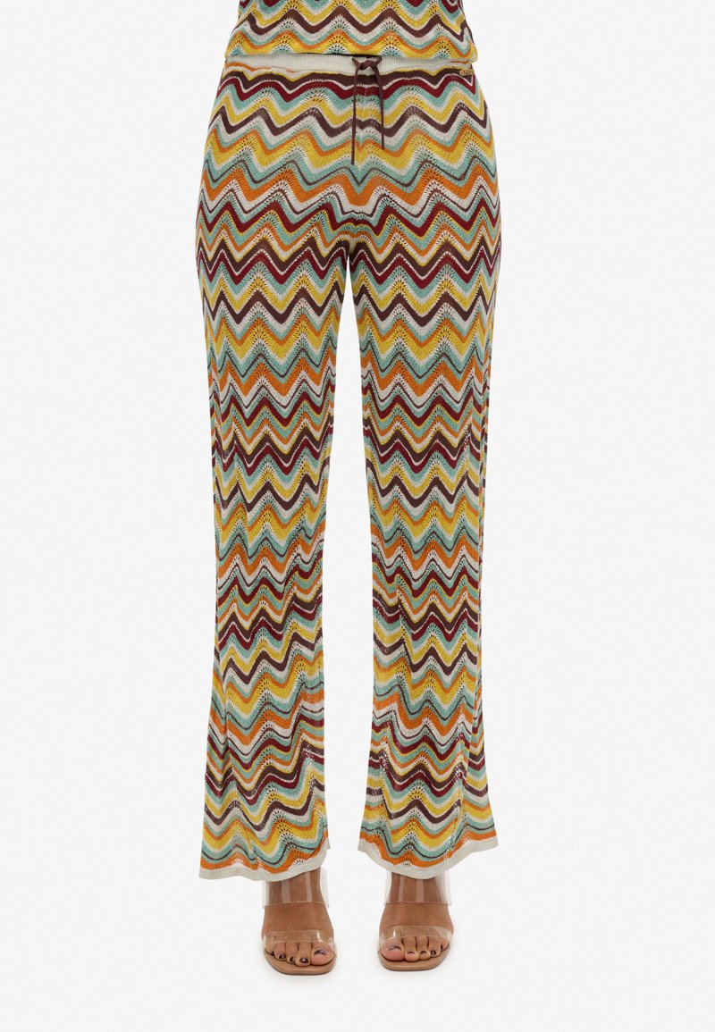 Bunt gemusterte Schlaghosen mit einem Zickzackmuster in Braun-, Orange-, Teal- und Cremetönen. Hergestellt aus strukturiertem Strickmaterial.