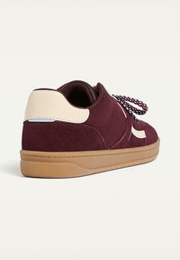 Bordowy zamszowy tenisówka z kremowym akcentem na pięcie, teksturowaną powierzchnią, gumową podeszwą i kontrastującymi sznurowadłami w wzory.