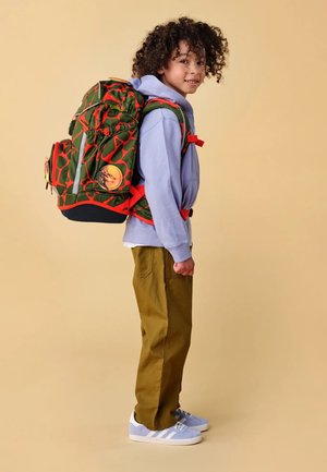 Grüner und orangefarbener Rucksack mit Muster, der mehrere Fächer, verstellbare Träger und reflektierende Akzente besitzt. Der Rucksack wird von einem Kind in einem lila Hoodie und olivfarbenen Hosen getragen.