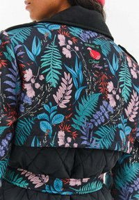 Čierna prešívaná bunda s farebným kvetinovým vzorom, ktorý obsahuje listy a kvety v tyrkysovej, fialovej a červenej farbe. Obsahuje čierny golier a nášivku s logom.
