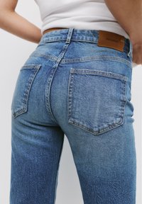 Ljusblå denimjeans med en klassisk femficksdesign, medelhög midja och en läderetikett på bakre midjebandet.