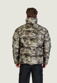 Padded camouflage bunda s vysokým límcem, obsahující kombinaci zelených a šedých tónů, prošívanou texturu a trojúhelníkový design na zadní straně.