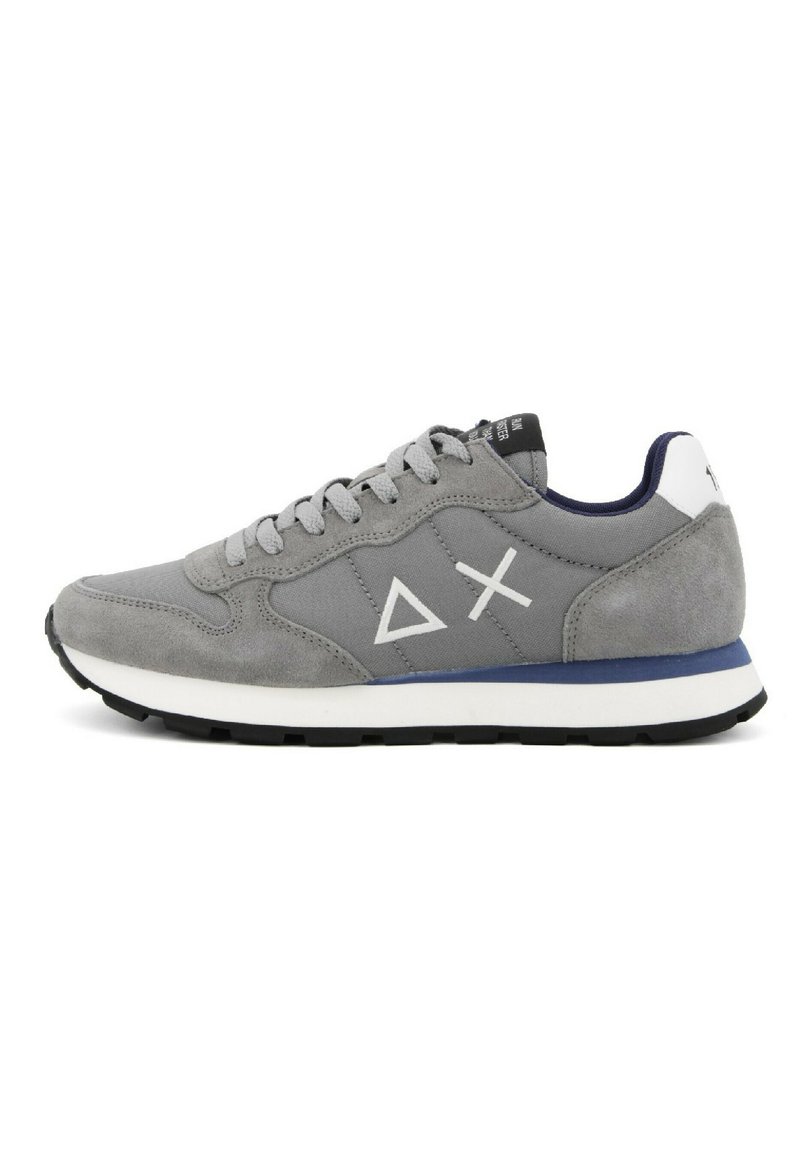 Sneaker atletica in suede grigio con logo bianco, dettagli blu navy e suola bianca a contrasto. Presenta un design con lacci e una parte superiore testurizzata.