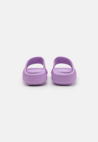 Purple rubber clogs featuring an open back, textured side, and a smooth surface, designed for comfort and ventilation.