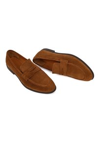 Mocasines de ante marrón con punta cosida, suela de goma plana y una tira decorativa en la parte superior. Forro interior suave.