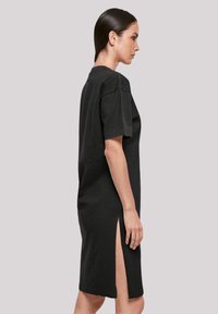 Schwarzes Baumwollkleid mit kurzen Ärmeln, taillierter Passform und seitlichen Schlitzen. Einfaches Design, knielang, glatte Textur und Rundhalsausschnitt.