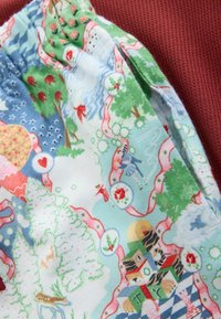 Krāsains rakstains audums ar kokiem, sirdīm un lentēm; gluda tekstūra ar gaiši zilu fonu un dzīvīgu ilustrāciju.