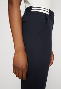 Námořnické kalhoty s upraveným střihem, s pruhovaným pasem, boční kapsou a hladkým povrchem. Malý logo akcent na zadní kapse.