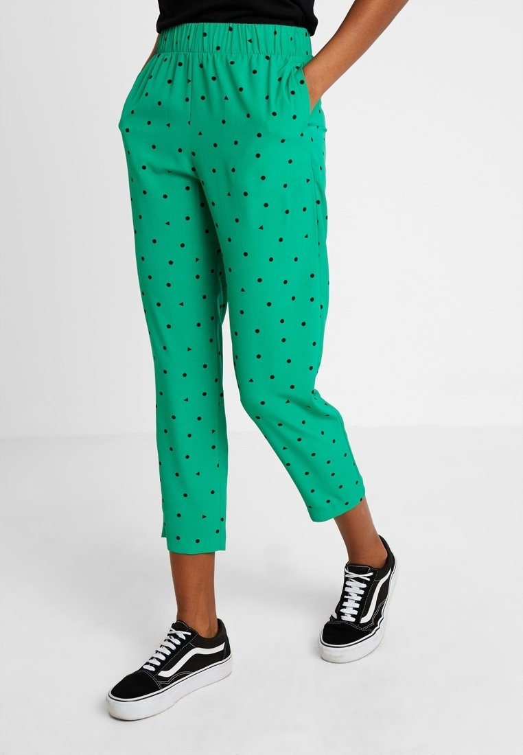 Green, cropped pants made of lightweight fabric with a textured finish. Features black triangle patterns and an elastic waistband.
