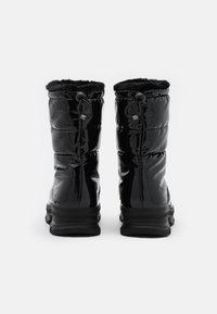 Bottes noires brillantes montantes avec un design matelassé, doublure en fausse fourrure et cordon de serrage ajustable en haut. Semelle noire texturée.